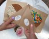 twee handen houden twee stroopwafels in papier met smartie & discodip topping